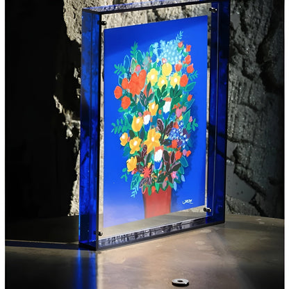 Tiefblauer Acrylrahmen mit Blumenstrauß-Druck vor einer Steinwand