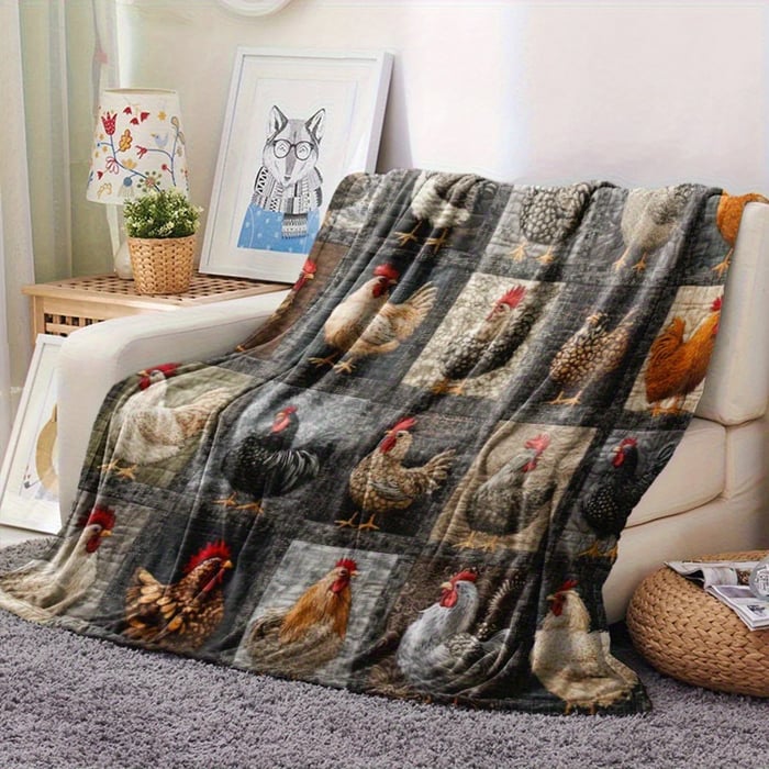 Decke mit Hühnermotiven auf einem Sofa, daneben Beistelltisch mit Lampe und Bilderrahmen 14