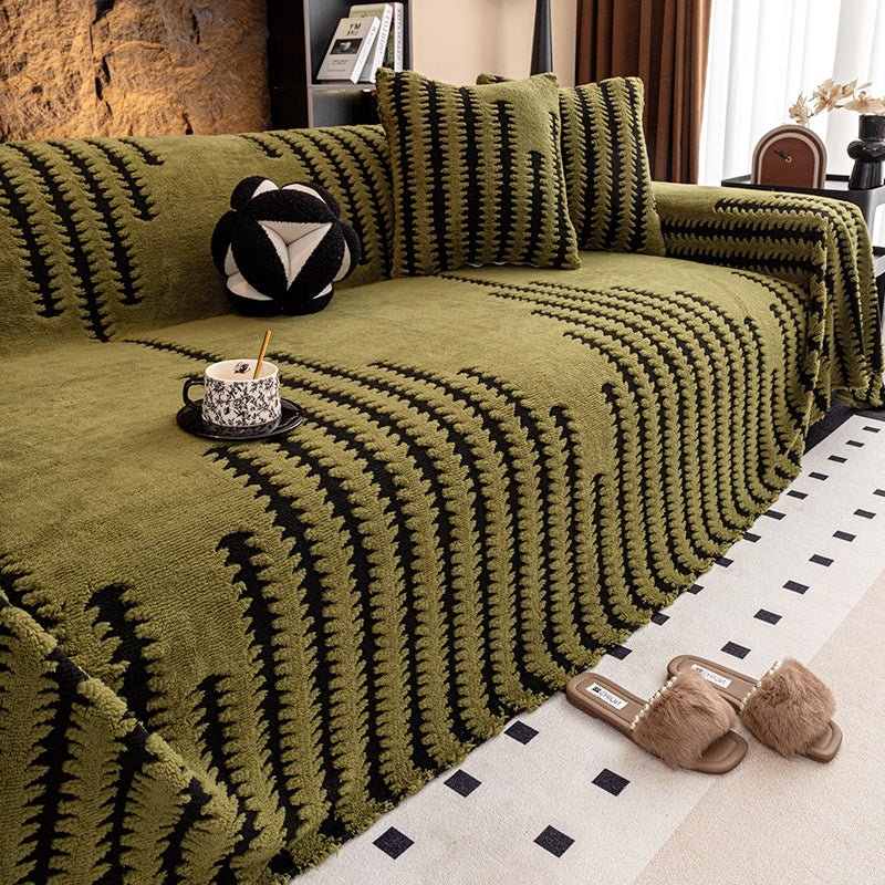 Olivgrüner Sofaüberwurf mit schwarzem Zackenmuster, auf dem Sofa Kissen und eine Tasse 11