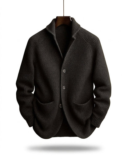 Schwarze Strickjacke in Rippstrick mit Knopfleiste und Taschen, frontal am Bügel schwebend fotografiert. 2