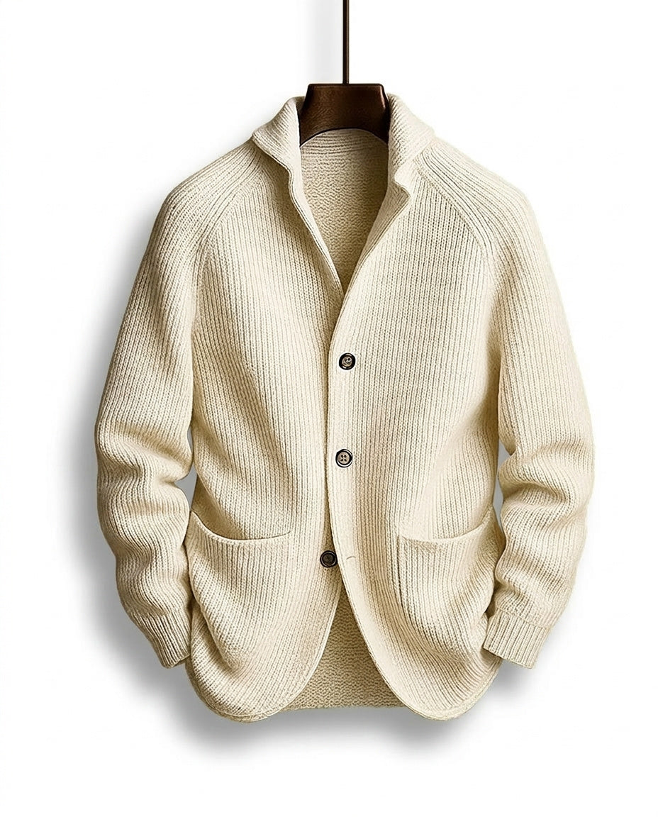 Cremeweiße Strickjacke mit grobem Rippmuster, Schalkragen und zwei aufgesetzten Taschen, frontal am Bügel. 5