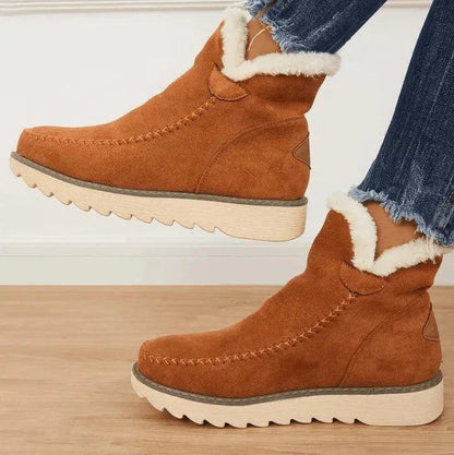 Braune Damen-Stiefeletten aus Leder mit weißem Plüschkragen und dicker Profilsohle, Seitenansicht.