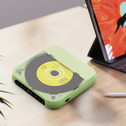 Grüner Player mit geschlossenem Deckel auf einem Holztisch neben einem aufgestellten Tablet und einem Stift. 12