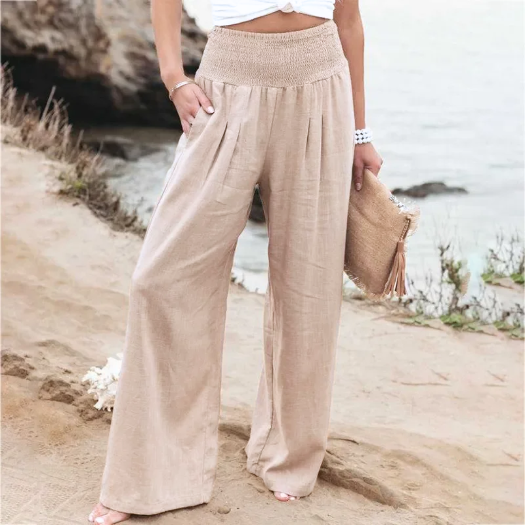 Frau in beigen Leinenhosen am Strand, Sommermode, lässiger Stil, weite Passform.