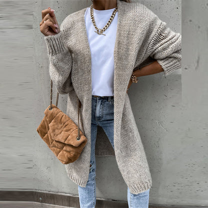 Frau in beigem Strickcardigan, weiße Bluse, Jeans, braune Umhängetasche, Goldkette.