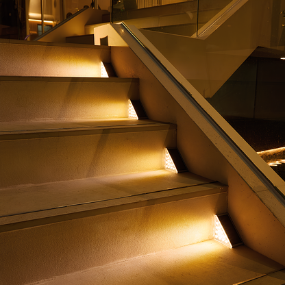 Beleuchtete Treppe mit LED-Stufenlichtern, modernes Design, Glasgeländer, Innenarchitektur.