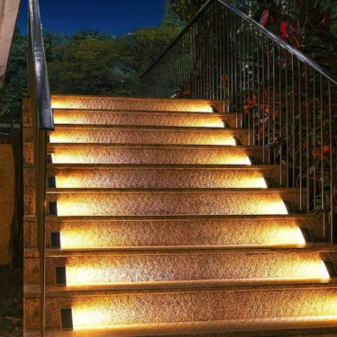 Beleuchtete Außentreppe bei Nacht, moderne LED-Stufenbeleuchtung, Edelstahlgeländer.