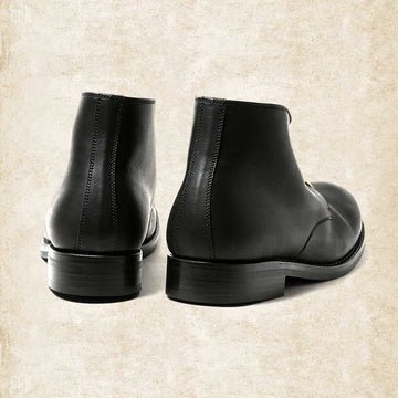 Braune Lederstiefel von hinten fotografiert, mit sichtbarer Fersennaht und stabilem, flachem Absatz mit profilierter Sohle.