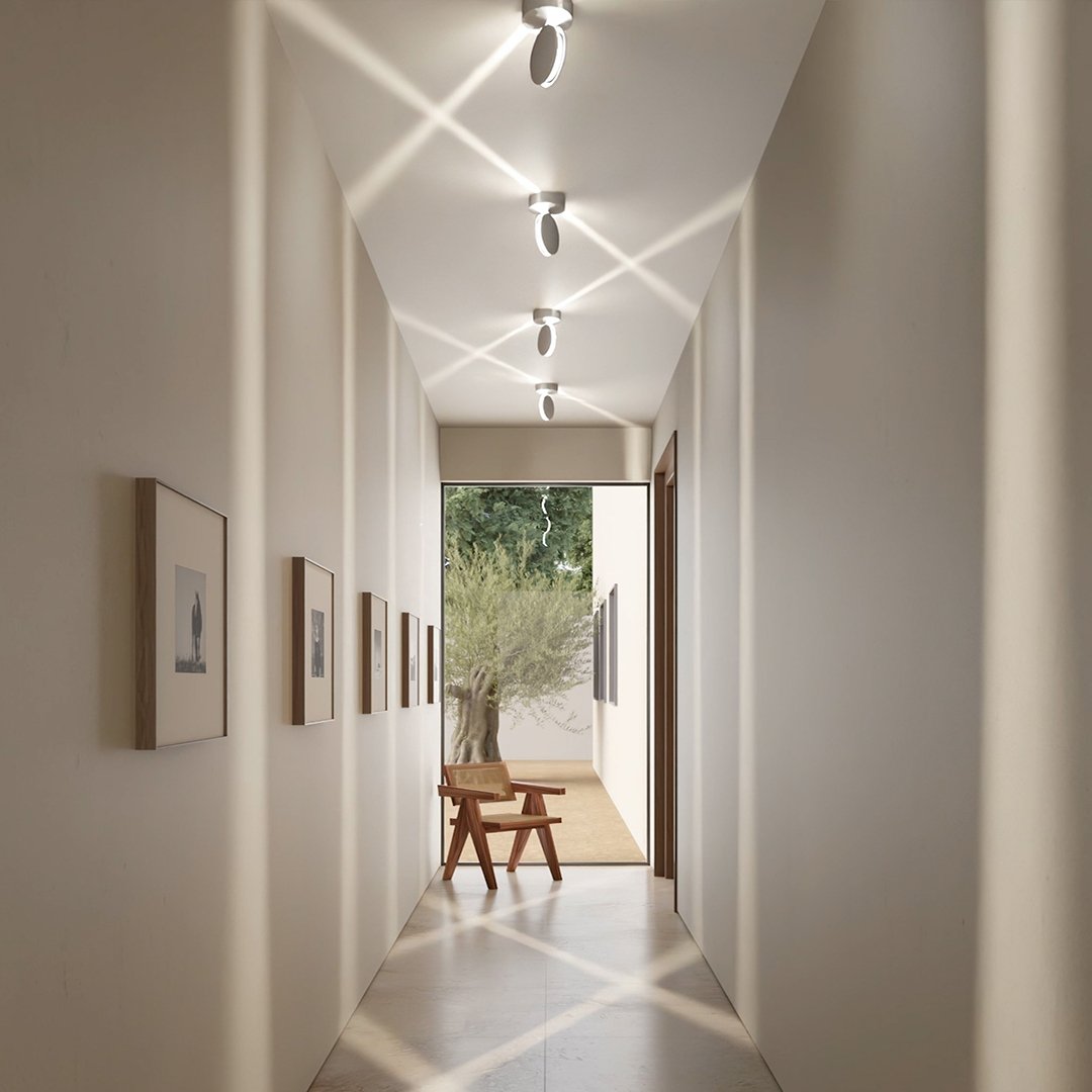 Flur, in dem die gedrehten Leuchtenköpfe sich überkreuzende Lichtstrahlen auf Decke, Wänden und Boden erzeugen. 7