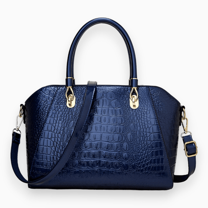 Dunkelblaue Krokodilleder-Handtasche mit goldenen Beschlägen und abnehmbarem Schulterriemen.
