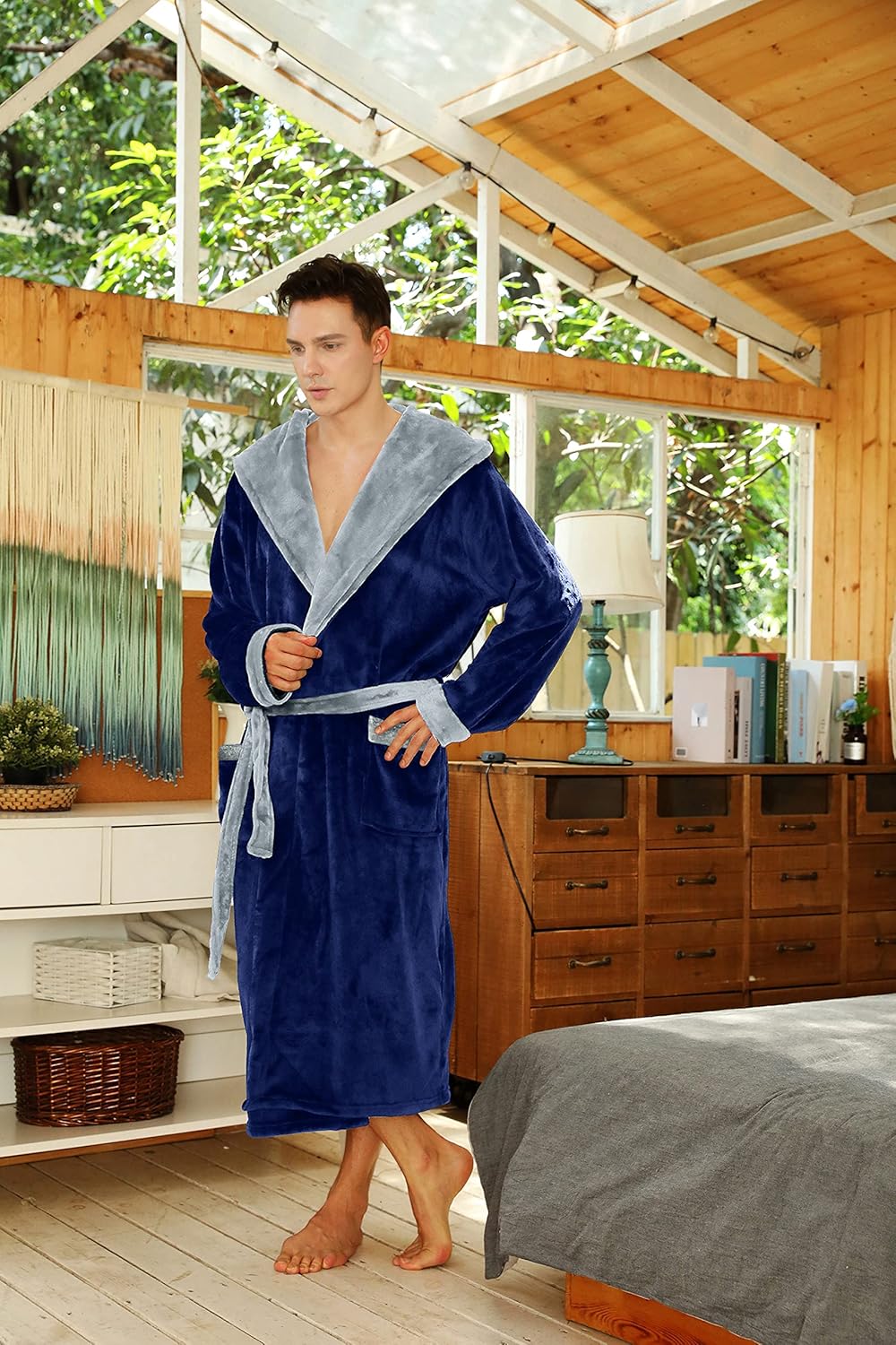 Mann im blauen Fleece-Bademantel mit grauem Kragen in modernem Schlafzimmer.