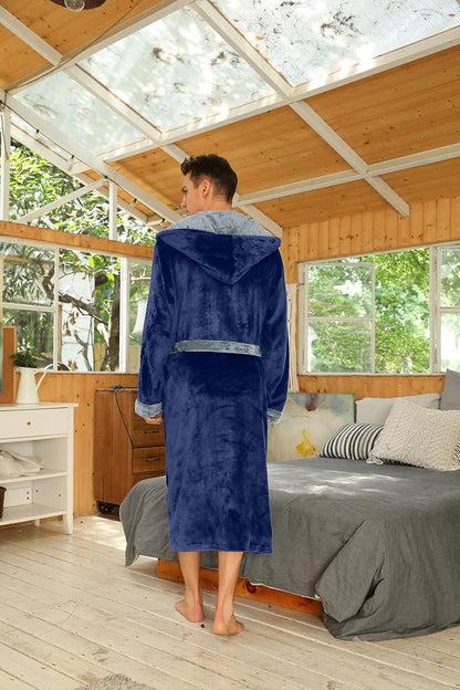 Mann im blauen Fleece-Bademantel mit Kapuze im Schlafzimmer, gemütliche Morgenroutine.