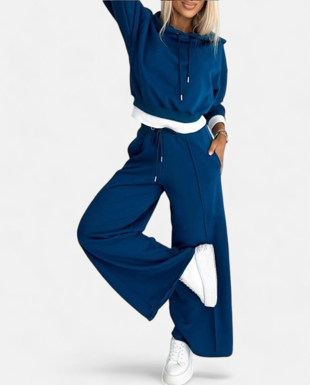 Frau in blauem Jogginganzug mit Kapuze und weißen Sneakers, Freizeitmode Damen.