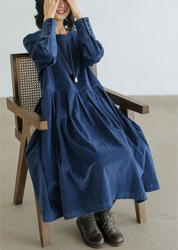 Frau in blauem Jeanskleid mit Taschen, Knöpfen, Herbstmode, sitzt auf Holzstuhl.