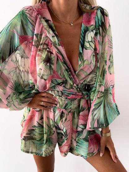 Frau in grün-rosa geblümtem Sommerkleid mit V-Ausschnitt und langen Ärmeln.