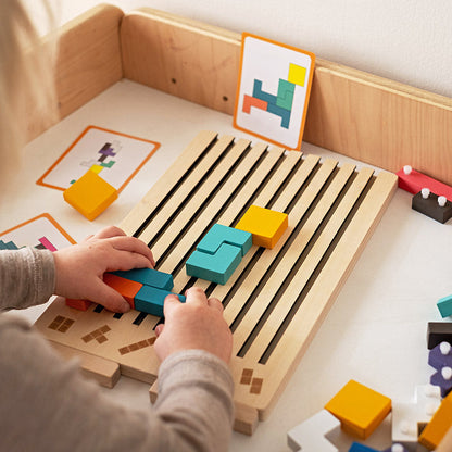 Holz-Tetris-Puzzlespiel mit Kind beim Einlegen farbiger Steine ins Holzbrett, Detail.