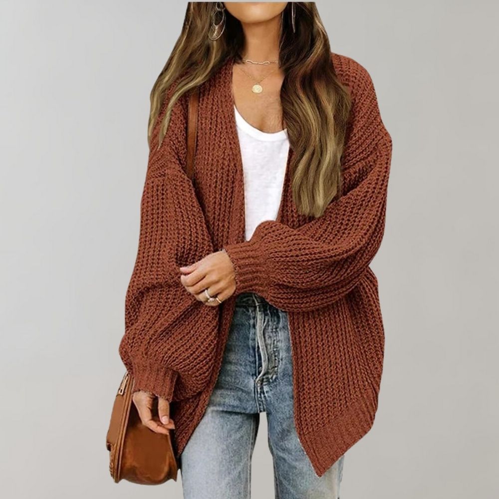 Frau in braunem Strickcardigan, weißem Top, Jeans, braune Tasche, lässiger Herbstlook.
