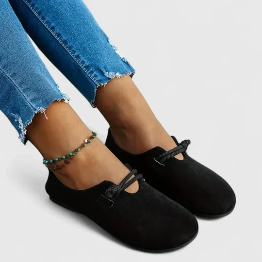 Schwarze Loafer mit runder Spitze und Kordelschlaufe, seitlich an den Füßen einer Frau in Jeans 2