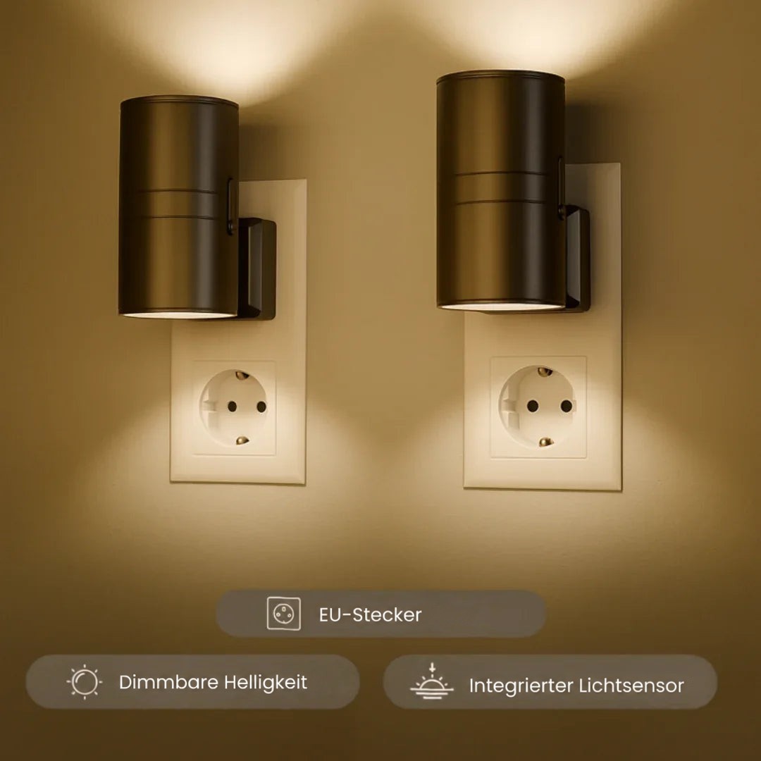 Zwei schwarze zylindrische Steckleuchten in Steckdosen strahlen warmes Licht nach oben und unten an die Wand 1