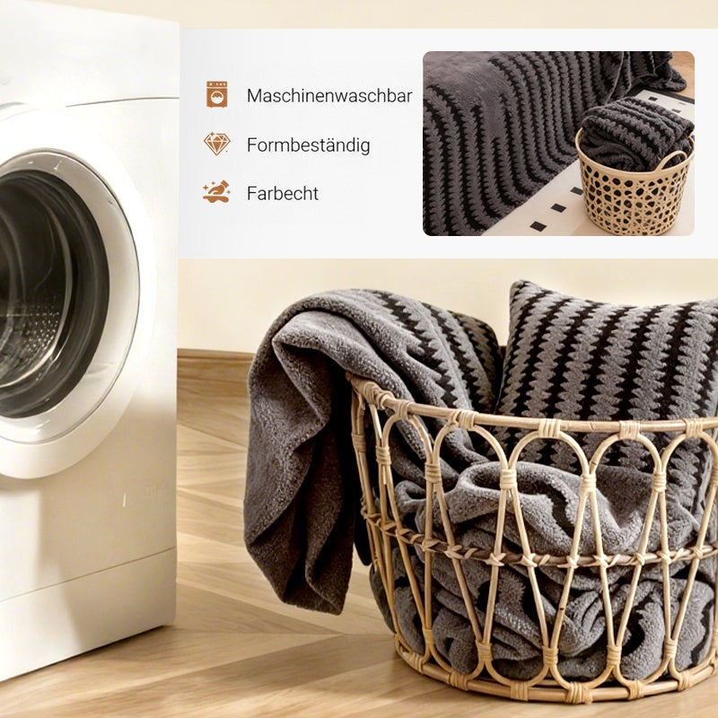 Waschmaschine und Korb mit gefaltetem grauem Überwurf und Kissen, Detailbild des Überwurfs auf dem Sofa 5