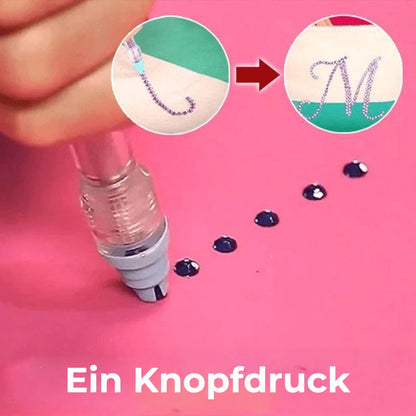 Nahaufnahme des Stifts, der per Knopfdruck dunkle Strasssteine auf rosa Untergrund ablegt, mit Buchstaben-M-Beispiel 3