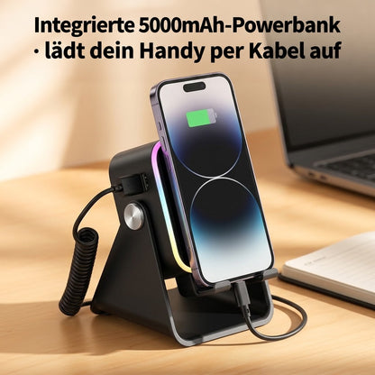 Schwarzer Ständer mit Smartphone, das über ein Spiralkabel am USB-Anschluss lädt, auf einem Schreibtisch neben Laptop und 5