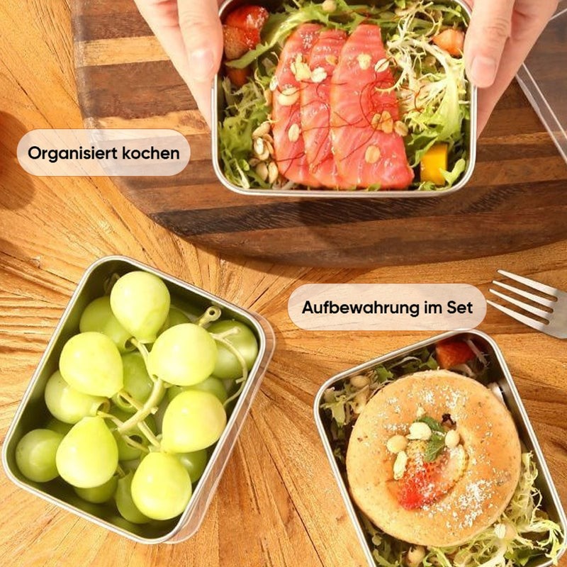 Draufsicht auf drei Edelstahlschalen auf Holztisch: Lachs mit Salat, grüne Trauben und ein Gebäck mit Salat. 8