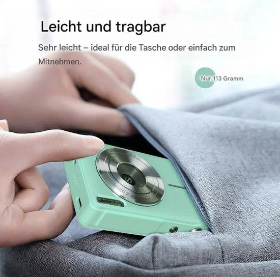 Hand schiebt die leichte mintgrüne Kamera in die Tasche einer grauen Jacke 4