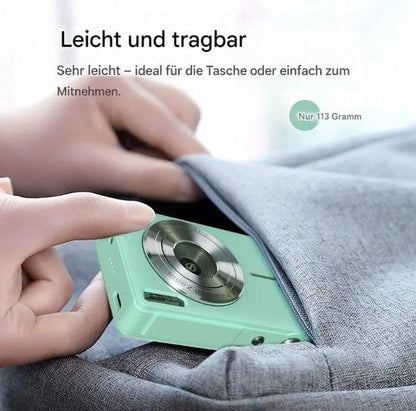 Hand schiebt die leichte mintgrüne Kamera in die Tasche einer grauen Jacke 4