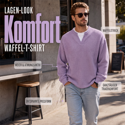 Mann in flieder Waffelstrick-Oberteil mit V-Ausschnitt und weißem Shirt darunter, lässig mit Händen in den Jeanstaschen auf der Straße. 1