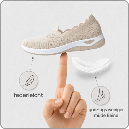 Beiger Strickschuh balanciert auf einem Fingerspitze neben einer Feder, Hinweis auf geringes Gewicht 3