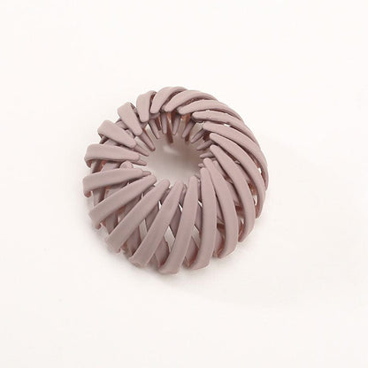 Matte Haarklammer in Altrosa mit spiralförmig angeordneten Rippen, einzeln vor hellem Hintergrund.