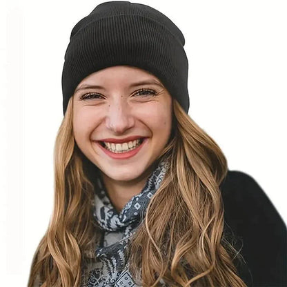 Lächelnde Frau mit langen welligen Haaren trägt eine schwarze Strickmütze und einen gemusterten Schal 3