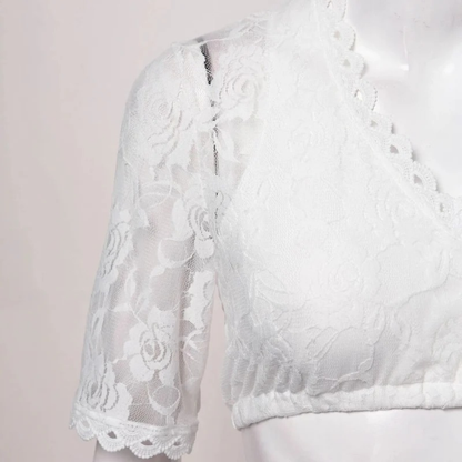 Detail der weißen Dirndl-Bluse aus floraler Spitze am Ärmel und Saum