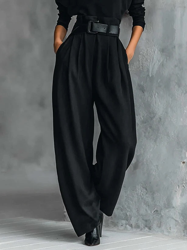 Detailansicht der schwarzen Hose mit weitem Bein, Bundfalten, seitlichen Taschen und breitem Gürtel am Bund 4
