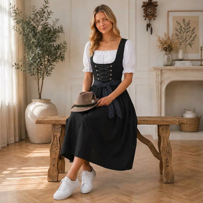 Frau im schwarzen Midi-Dirndl mit Filzhut mit Feder auf dem Schoß, Detail