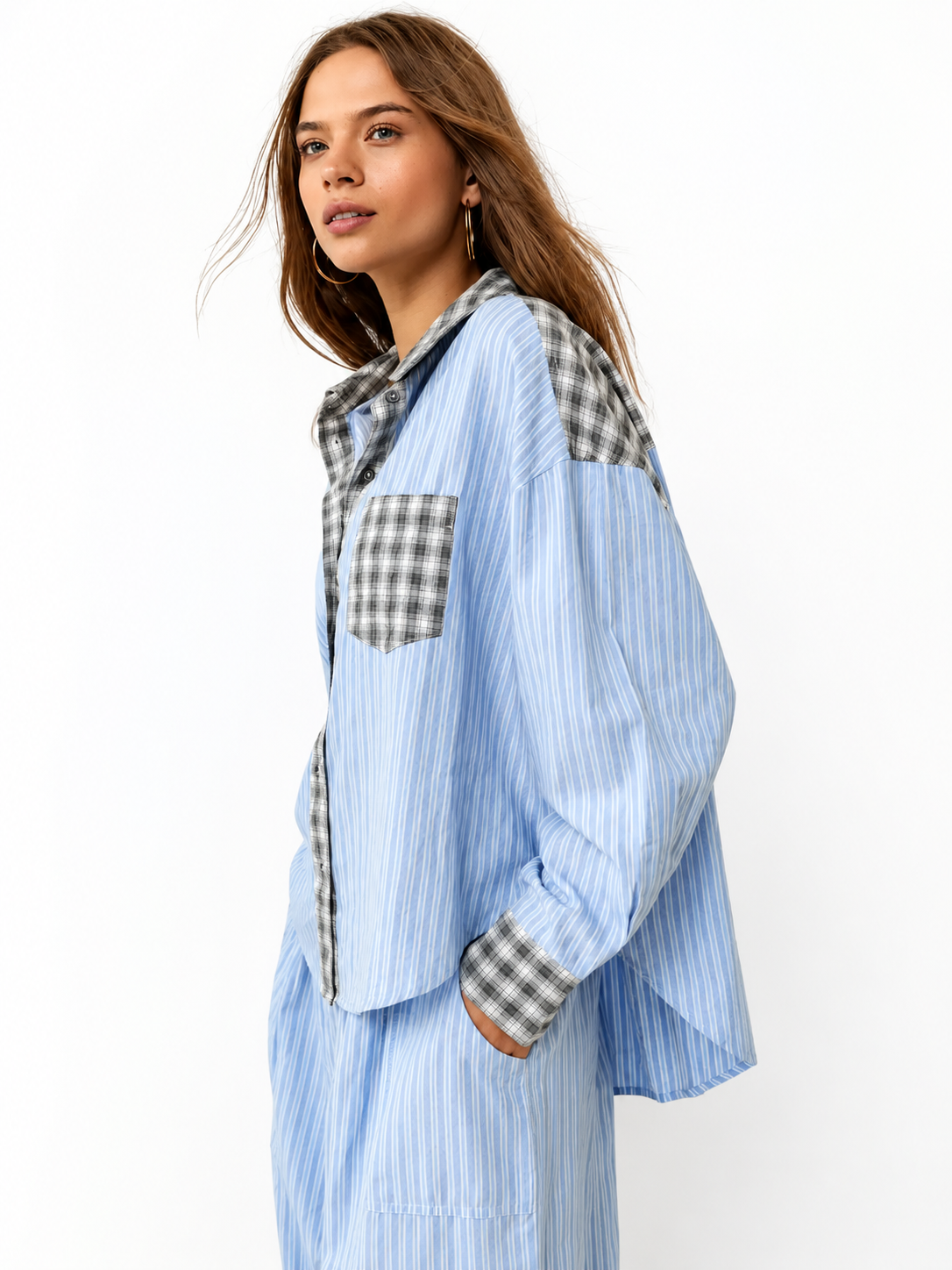 Seitliche Nahaufnahme eines blau gestreiften Pyjama-Hemds mit grau karierten Einsätzen an Kragen, Schulter, Brusttasche und Manschette