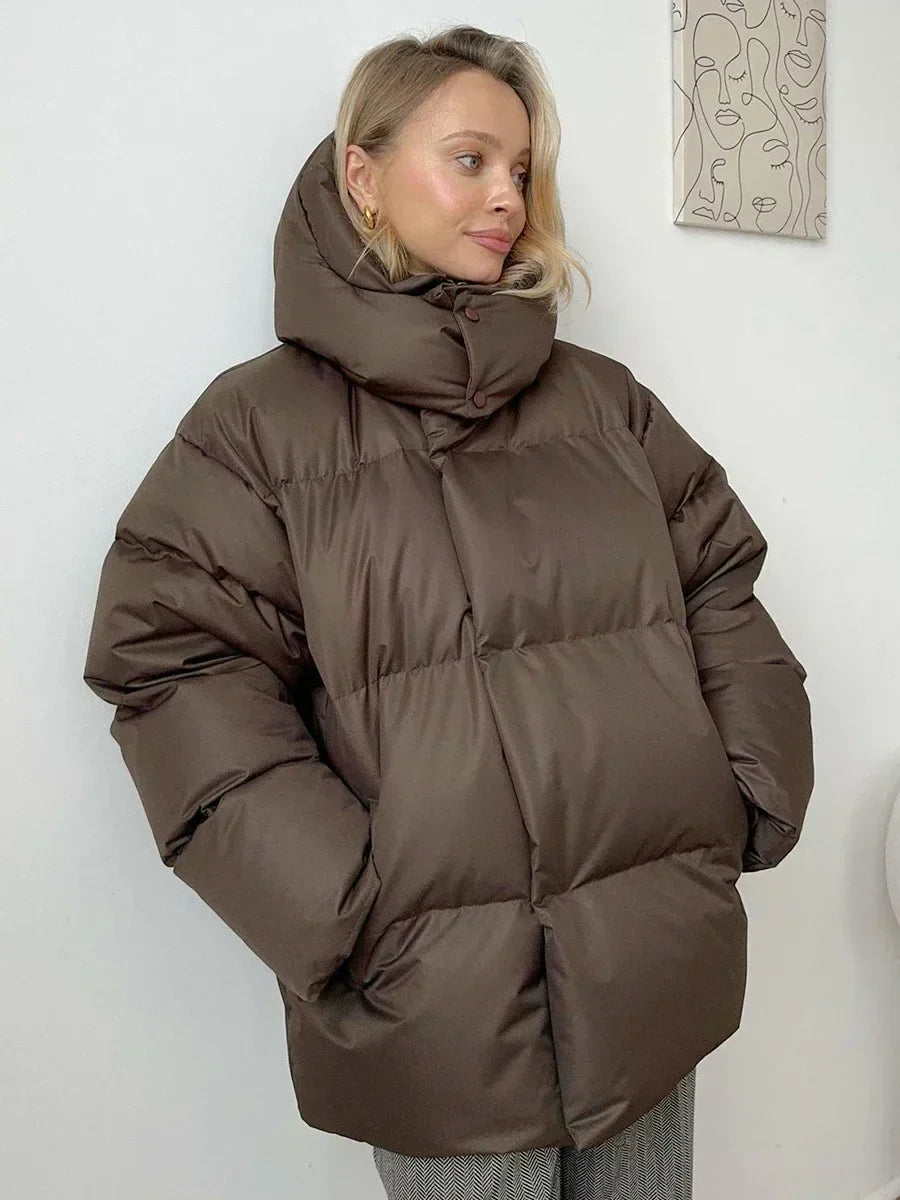 Frau in brauner Daunenjacke, Wintermode, warm, stilvoll, Kapuze, gemütlich, Damenbekleidung.