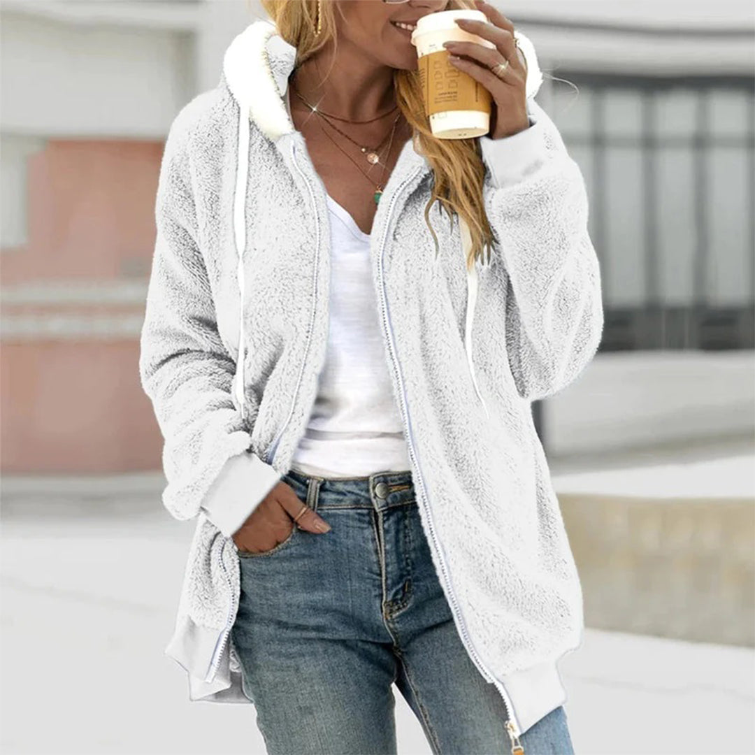 Frau in weißem Fleece-Hoodie mit Kaffeebecher, lässige Mode, Herbstkleidung.