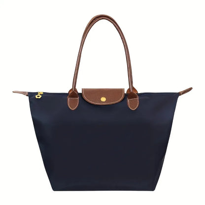 Dunkelblaue Damenhandtasche aus Nylon mit braunen Ledergriffen und Klappe.