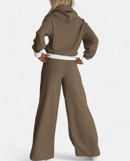 Frau in braunem Jogginganzug, Kapuzenpullover und weite Hose, Rückansicht, Freizeitmode.
