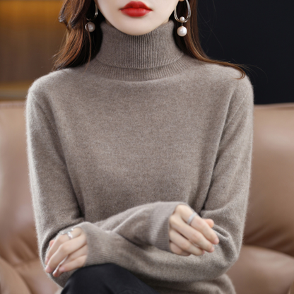 Taupefarbener Rollkragenpullover am sitzenden Model mit geripptem Kragen und Ärmelbündchen.