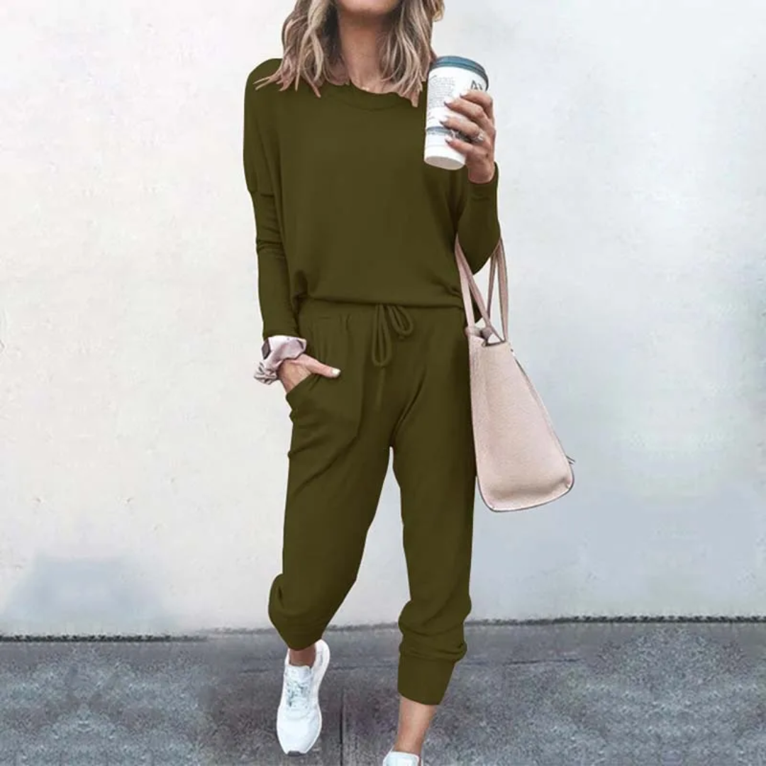 Frau in olivgrünem Freizeitanzug mit Kaffeebecher und beiger Tasche, lässige Mode.