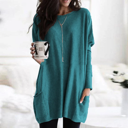 Frau in türkisfarbenem Oversize-Pullover mit Kaffeetasse, gemütliche Herbstmode.