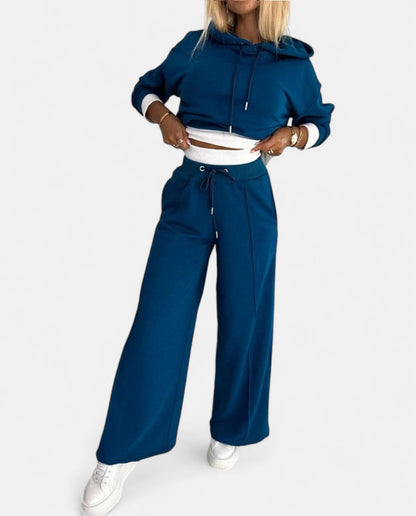 Frau in blauem Jogginganzug, Kapuzenpullover, weite Hose, weiße Sneaker, Freizeitmode.