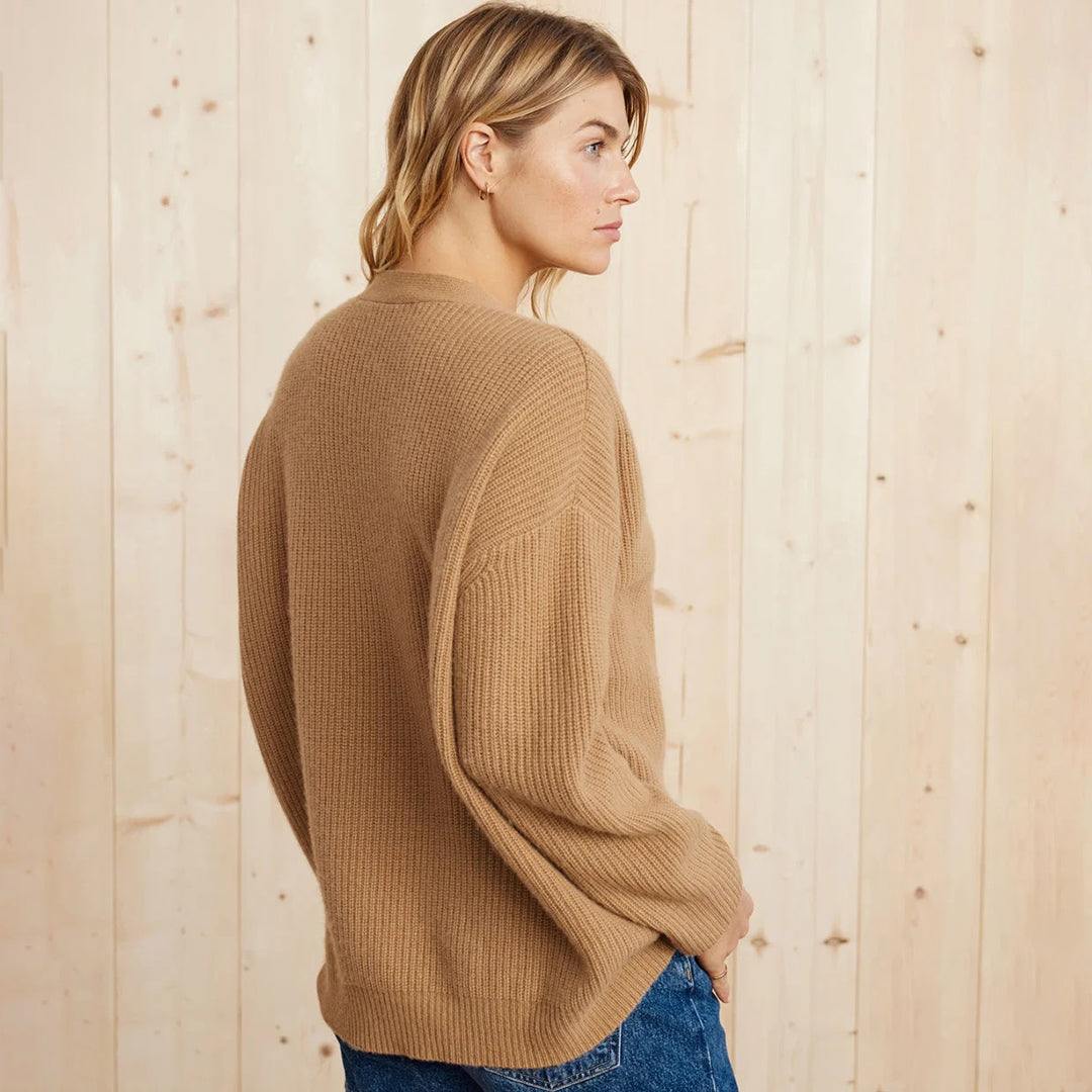 Frau in beigem Strickpullover, Holz-Hintergrund, lässige Mode, Herbst-Winter-Outfit.
