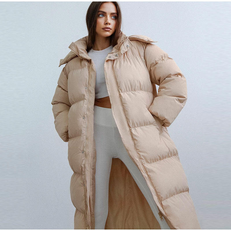 Frau in beigem Daunenmantel, Wintermode, lange Jacke, warm, stilvoll, Damenbekleidung.