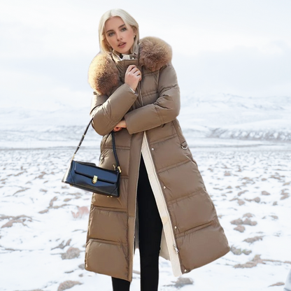 Frau in braunem Daunenmantel mit Pelzkragen, schwarze Handtasche, schneebedeckte Landschaft.