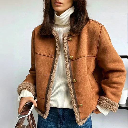 Model trägt die braune Wildlederjacke offen über weißem Rollkragenpullover und Jeans, Handy und Tasche in der Hand 1