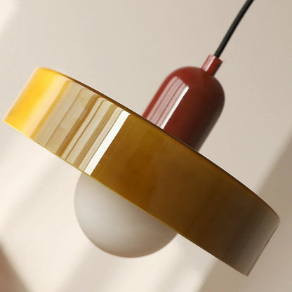 Nahaufnahme des glänzenden gelb-olivfarbenen Glasschirms mit roter Kappe und der darunter sichtbaren weißen Kugel. 28
